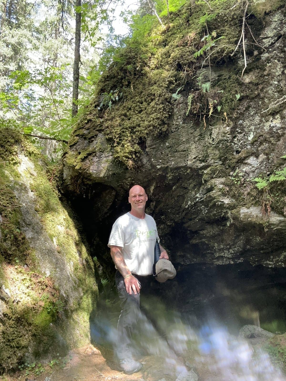 Pegel in einer moosbewachsenen Felshöhle im Wald